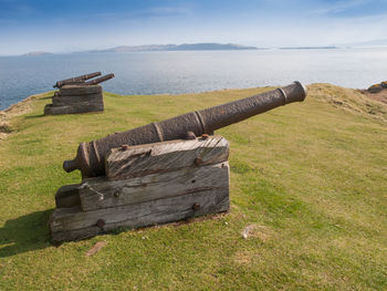 Old ruin on field by sea against sky