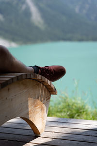 Low section of man relaxing by lake