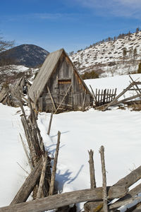 Wooden house on snowcapped mountains against sky