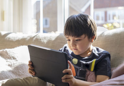 Rear view of boy sitting at home