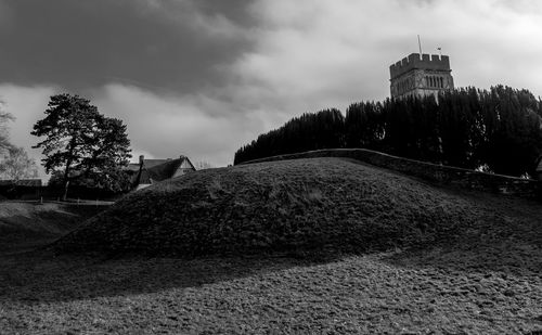 Low angle view of historic building and hill against sky