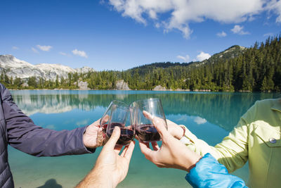 Family of four cheers with red wine at the lake.