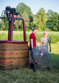 Mother and son with electric fan standing on field