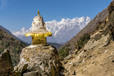 Panoramic view of cross on rock against sky