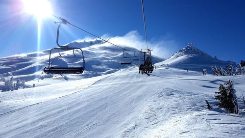 Ski lift on snowcapped mountains during sunny day