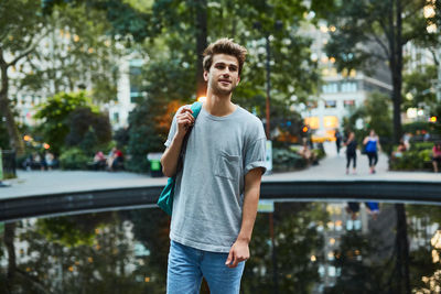 Portrait of smiling young man standing against trees