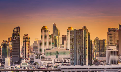 Modern buildings against sky during sunset