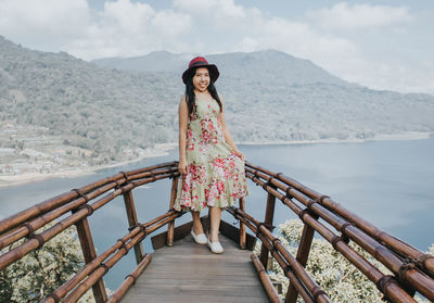 Woman standing on railing against mountains