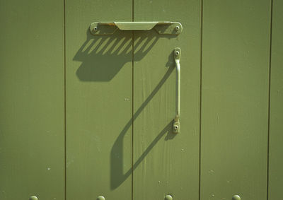 Close-up of handle on green wooden door