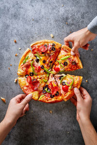 Cropped hands of friends having pizza on table