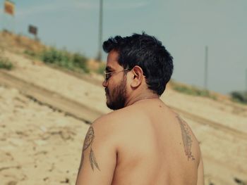 Shirtless man with tattoo at beach