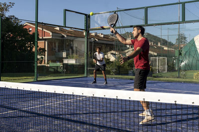 Men playing paddle tennis at sports court