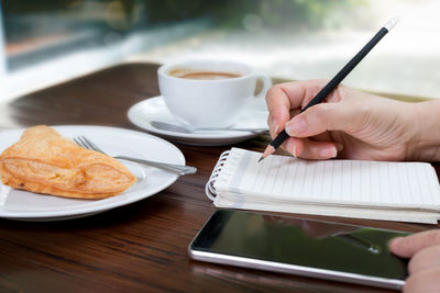 Close-up of hand holding coffee cup on table