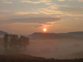 Scenic view of silhouette landscape against sky during foggy sunrise 