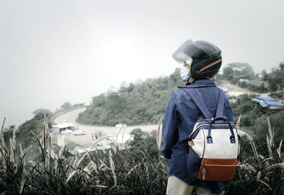 Rear view of man standing by mountain against sky