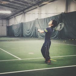 Full length of boy playing tennis in court