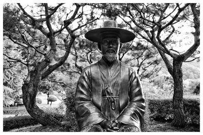 Portrait of man standing by plants against trees