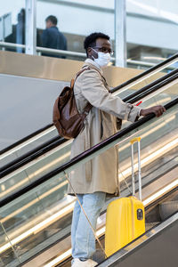 Man wearing mask standing on escalator