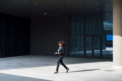 Businesswoman holding tablet pc walking outside office building