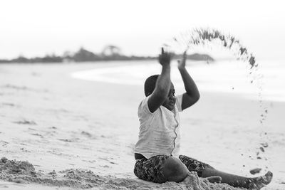 Rear view of woman sitting on beach