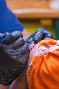 Cropped image of artist tattooing on customer body part