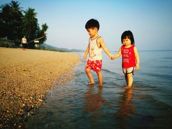 Sibling on shore against sky