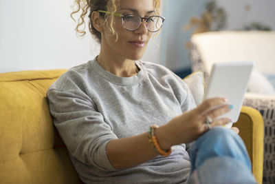 Young woman using mobile phone while sitting on sofa at home