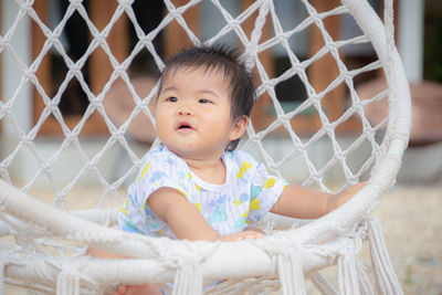 Portrait of cute baby girl behind fence