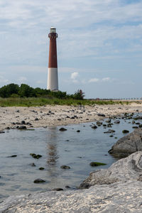 Lighthouse by sea against sky