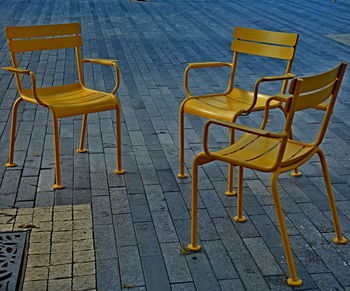 High angle view of empty chairs and tables at sidewalk cafe