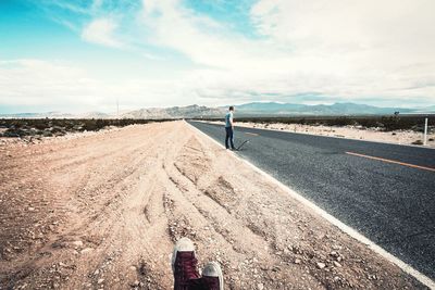 Rear view of man standing on road against sky