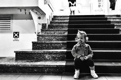 Cute girl with pacifier sitting on stairs