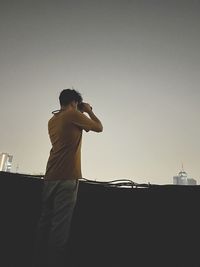 Rear view of man standing against clear sky