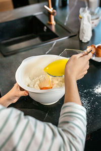 Cropped hand of person preparing food in kitchen