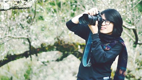 Young woman wearing sunglasses standing against plants