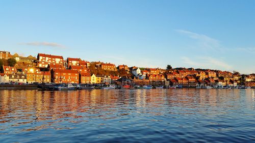 River by houses in town against blue sky