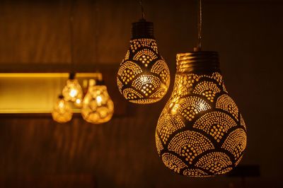 Close-up of patterned illuminated light bulbs hanging in restaurant