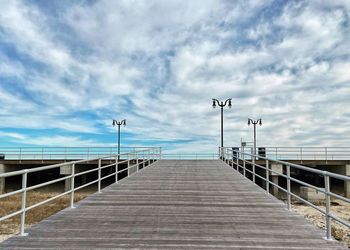 Empty pier over sea against sky