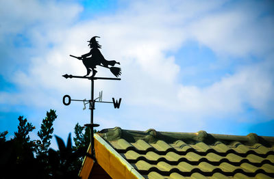 Low angle view of weather vane against blue sky