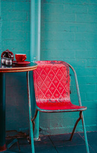Empty chair against turquoise wall