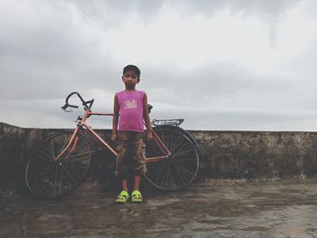 Full length portrait of man standing on bicycle against sky