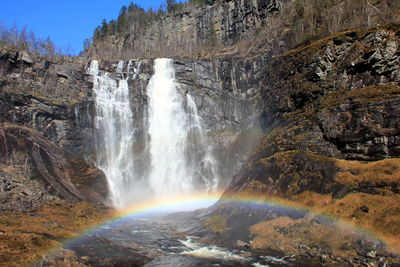 Rainbow over waterfall against mountains