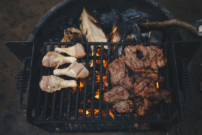 Chicken and meat on a grill at a campsite