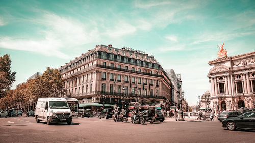 Cars on city street against sky