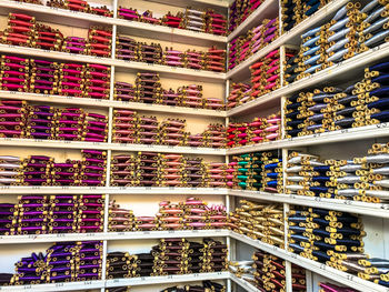 Multi colored threads in shelves at store for sale