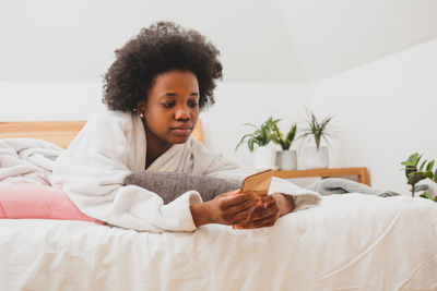 Portrait of young woman lying on bed at home