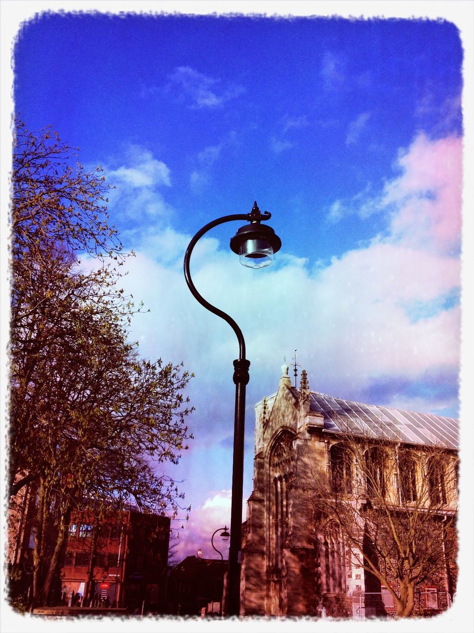 low angle view, building exterior, built structure, architecture, transfer print, sky, street light, auto post production filter, cloud - sky, communication, cloud, lighting equipment, road sign, day, tree, cloudy, city, outdoors, guidance, tower