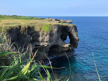Rock on sea shore against sky