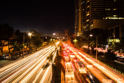 Light trails on city street amidst buildings at night