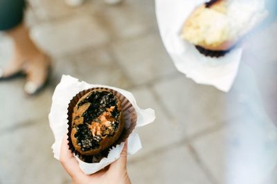 Cropped hand holding cupcake in city